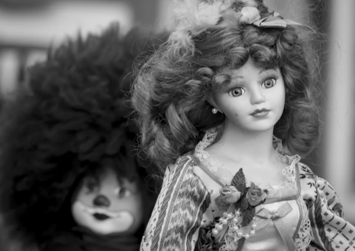 Porcelain doll in a lace dress with a furry doll behind it